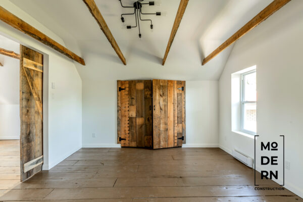 Chambre rénovée avec poutres en bois apparentes.