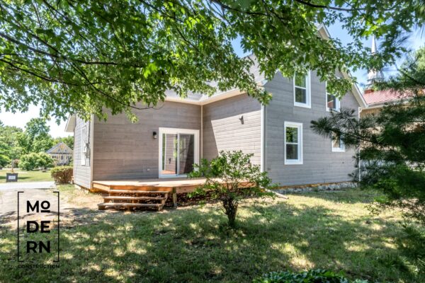 Maison moderne avec terrasse en bois, cadre verdoyant.
