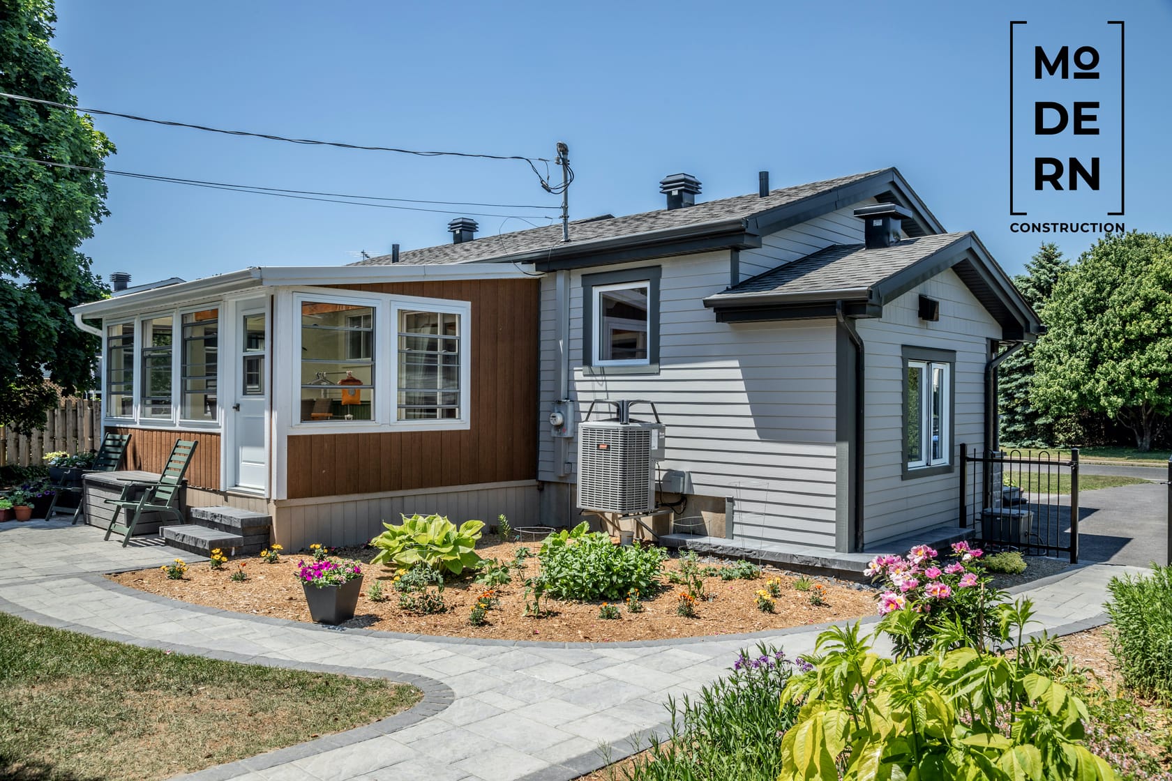Maison moderne avec jardin fleuri devant.