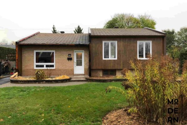 Maison en brique avec jardin devant.