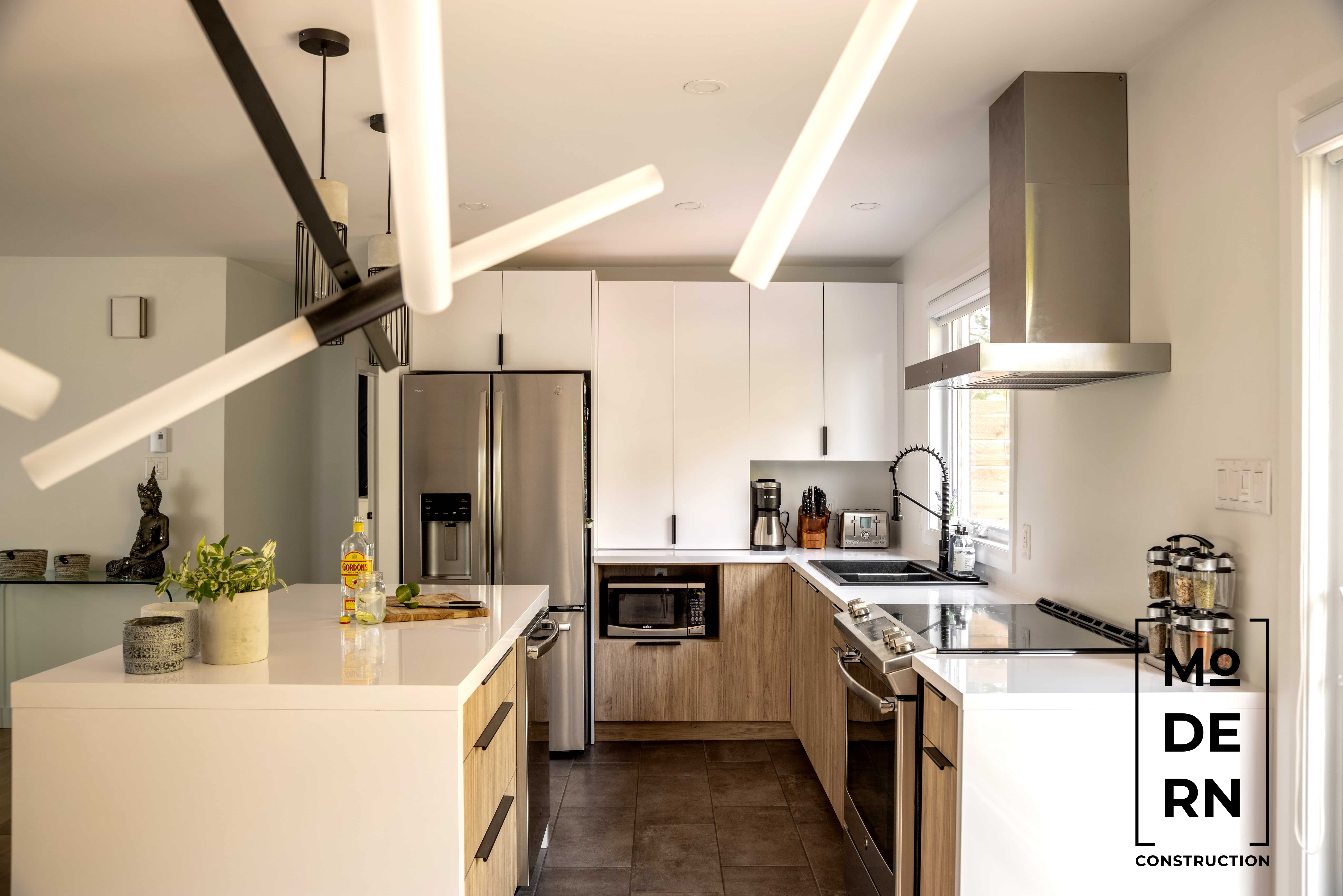 Cuisine moderne avec îlot central et éclairage contemporain.