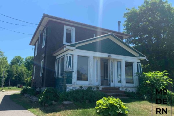 Vieille maison devant un jardin verdoyant.