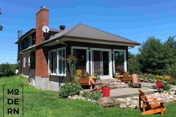 Maison en brique avec terrasse et jardin fleuri.