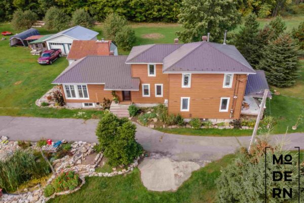 Grande maison en bois, jardin verdoyant autour.