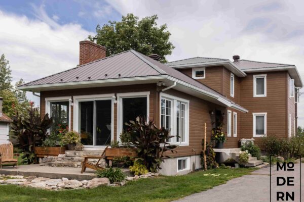 Maison moderne à toit métallique, jardin fleuri.