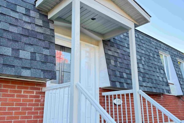 Porche d'entrée avec toit et rampe blanche.