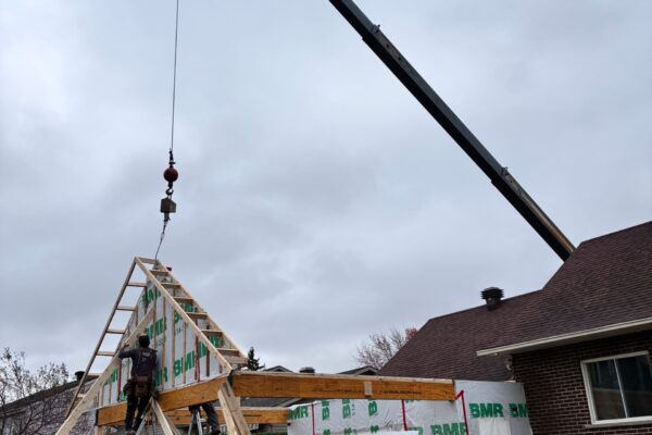 Grue et ouvriers construisant une charpente en bois.
