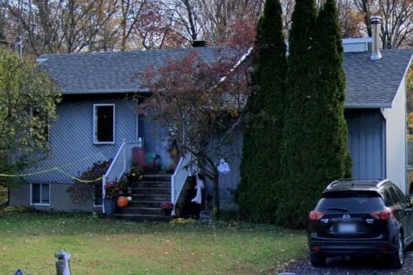 Maison avec voiture garée devant, arbres environnants.